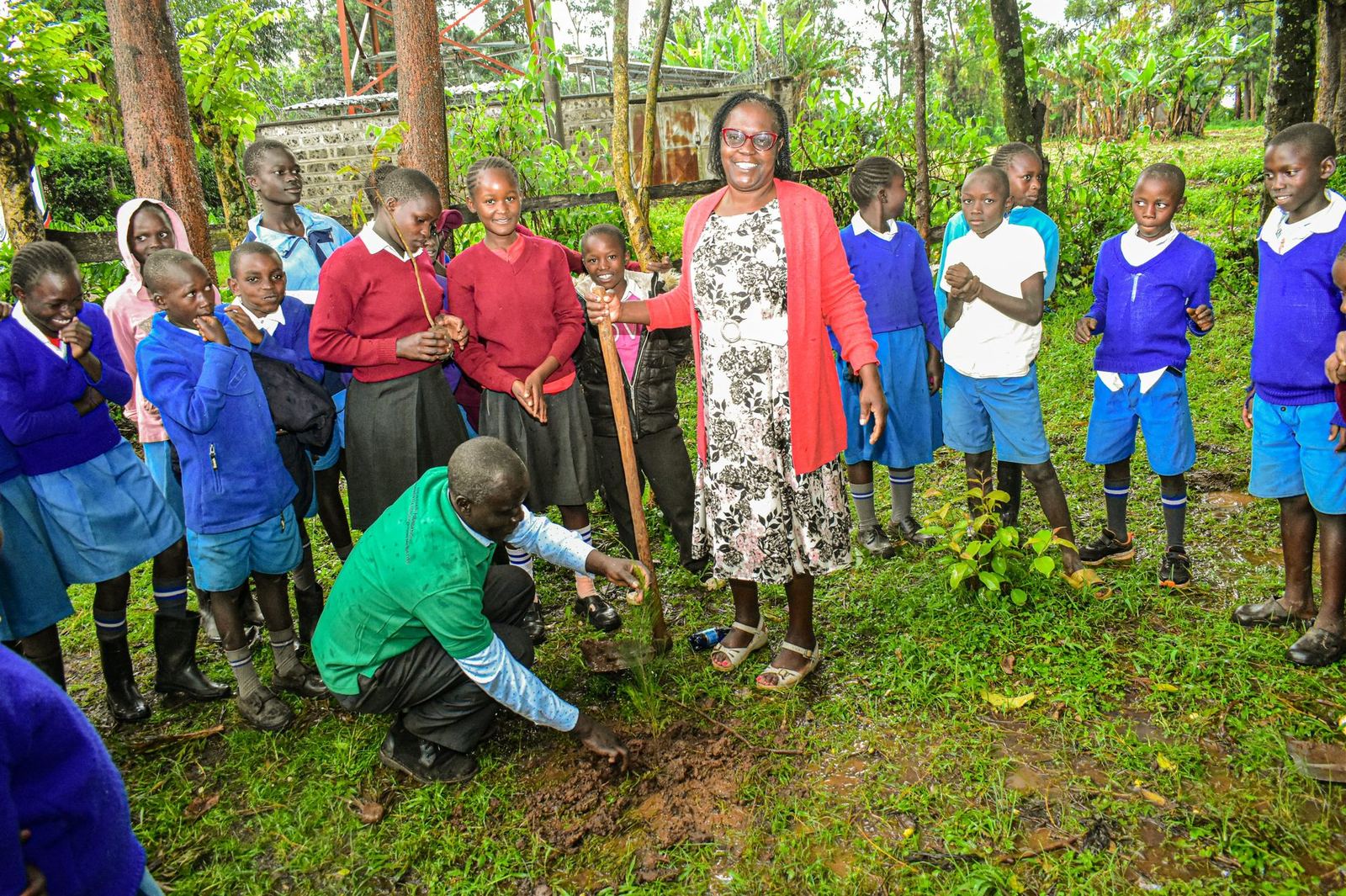 Woman and children planting a tree seedling in Kenya community program